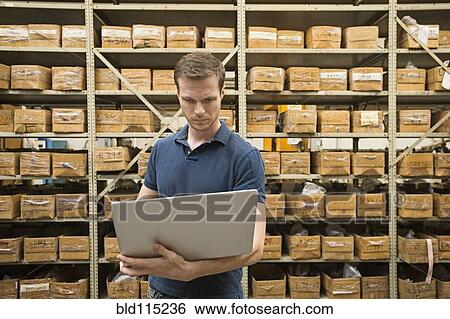 Stock Photograph - Caucasian worker using laptop in textile factory. Fotosearch