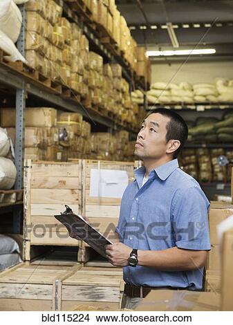 Picture - Chinese worker using clipboard in textile factory. Fotosearch