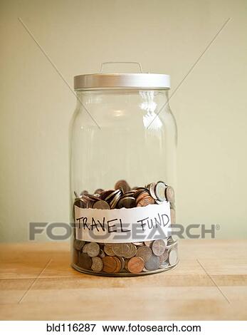 Stock Photo - Coins in 'travel fund' jar. Fotosearch