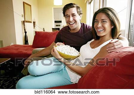 Couple eating popcorn on sofa View Large Photo Image Picture - Couple eating popcorn on sofa. Fotosearch