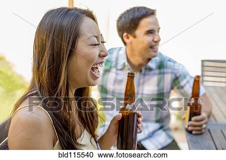 Stock Image - Couple having beers in backyard. Fotosearch