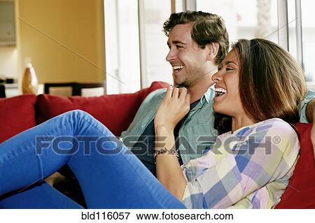 Stock Photo - Couple laughing on sofa. Fotosearch