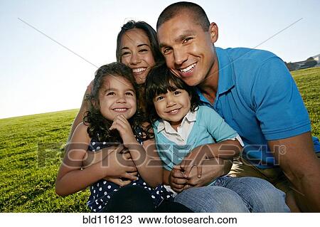 Stock Image - Family smiling together in field. Fotosearch