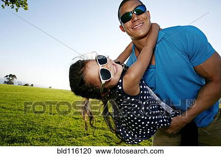 Stock Image - Father and daughter playing in field. Fotosearch
