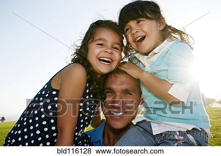 Stock Photo - Father and daughters smiling in field. Fotosearch