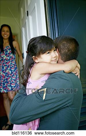 Stock Photograph - Girl hugging soldier father at door. Fotosearch