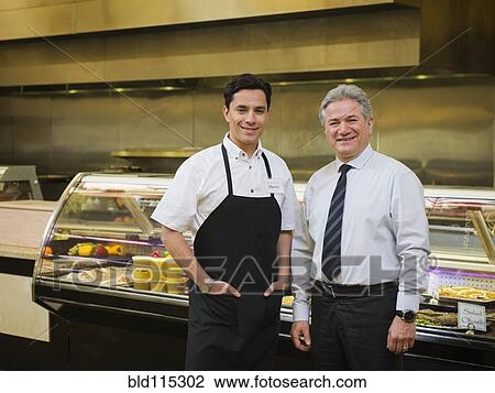 Stock Image - Hispanic businessman and worker in kitchen. Fotosearch