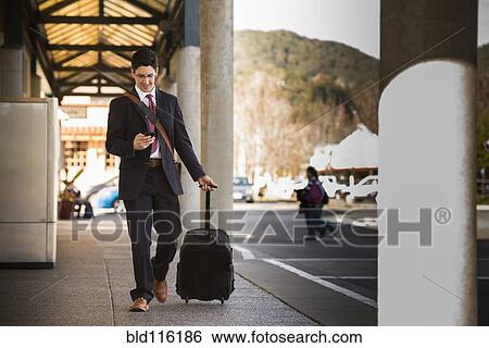 Hispanic businessman rolling luggage View Large Photo Image Stock Photograph - Hispanic businessman rolling luggage. Fotosearch