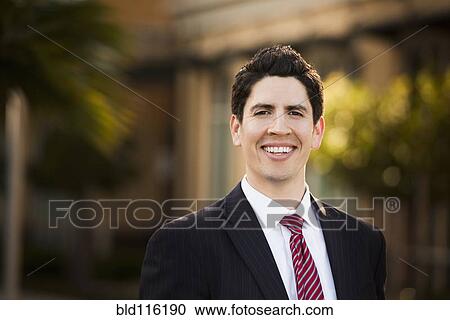 Stock Image - Hispanic businessman smiling outdoors. Fotosearch