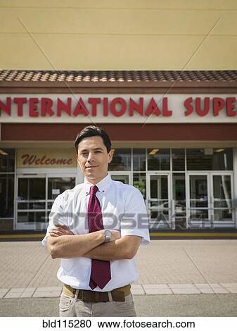 Hispanic businessman standing outside grocery store View Large Photo Image Stock Image - Hispanic businessman standing outside grocery store. Fotosearch