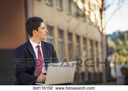 Stock Image - Hispanic businessman using laptop. Fotosearch