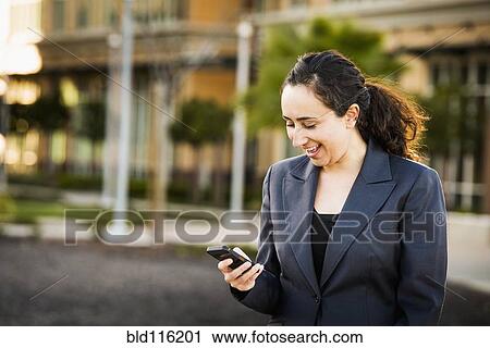 Stock Image - Hispanic businesswoman using cell phone. Fotosearch