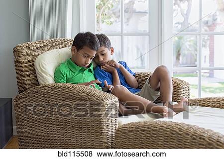 Stock Photo - Hispanic children relaxing in armchair. Fotosearch