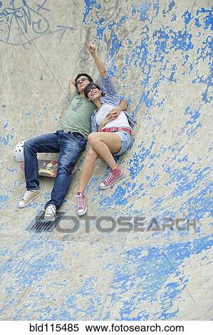 Stock Photography - Hispanic couple laying in skatepark. Fotosearch