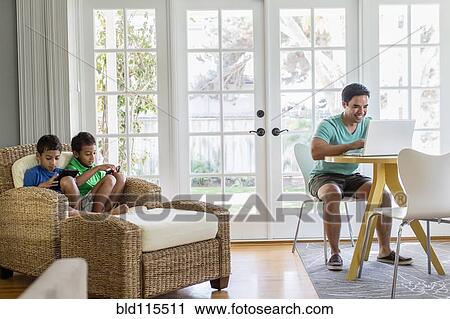 Stock Image - Hispanic family relaxing in living room. Fotosearch