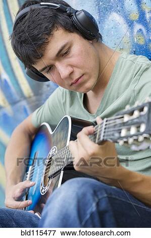 Stock Photo - Hispanic man playing guitar. Fotosearch