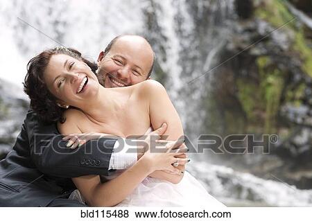 Stock Photo - Hispanic newlyweds hugging by waterfall. Fotosearch