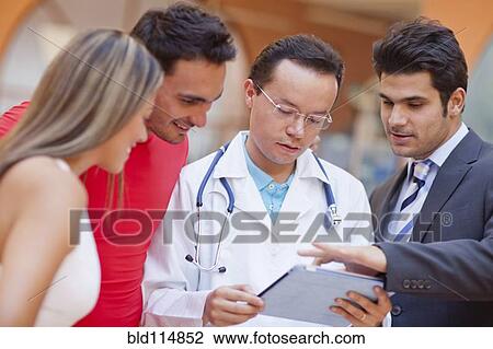 Stock Image - Hispanic people and doctor using tablet computer in gym. Fotosearch