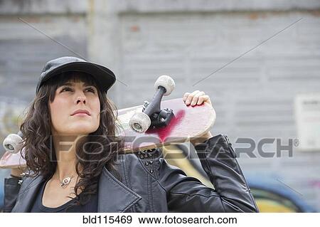 Hispanic woman holding skateboard outdoors View Large Photo Image Stock Photo - Hispanic woman holding skateboard outdoors. Fotosearch