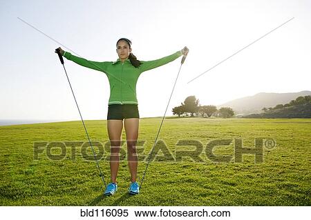 Stock Photography - Hispanic woman jumping rope in rural landscape. Fotosearch
