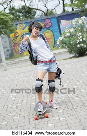 Picture - Hispanic woman posing on skateboard. Fotosearch