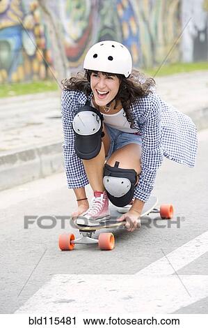 Stock Image - Hispanic woman riding skateboard. Fotosearch
