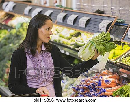 Stock Photograph - Hispanic woman shopping for produce in grocery store. Fotosearch