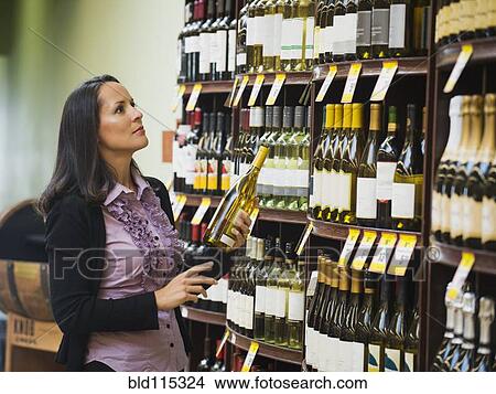 Picture - Hispanic woman shopping for wine. Fotosearch