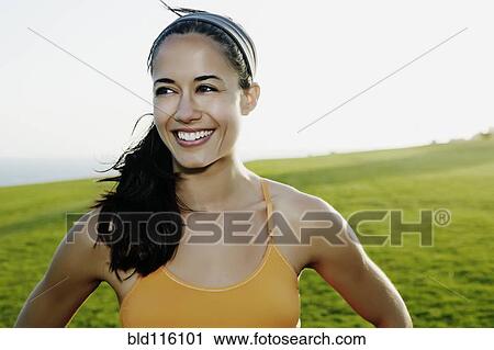 Stock Image - Hispanic woman smiling in field. Fotosearch