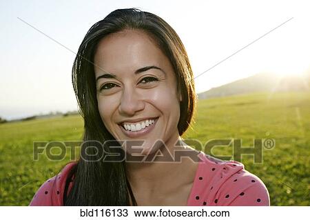Stock Image - Hispanic woman smiling outdoors . Fotosearch