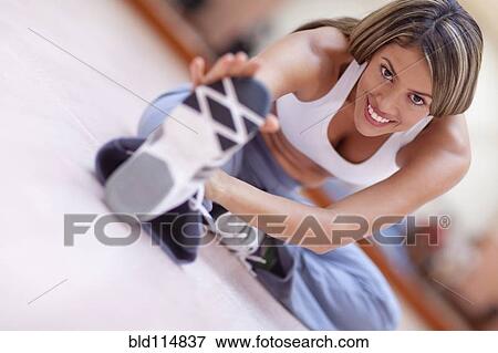 Stock Photo - Hispanic woman stretching in gym. Fotosearch