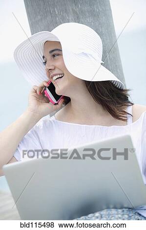 Hispanic woman using cell phone and laptop View Large Photo Image Stock Photo - Hispanic woman using cell phone and laptop. Fotosearch