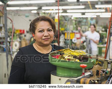 Stock Photography - Hispanic worker operating machinery in textile factory. Fotosearch
