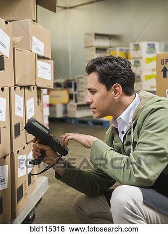 Stock Photo - Hispanic worker scanning boxes in walk-in freezer. Fotosearch