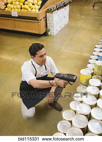 Stock Image - Hispanic worker scanning items in grocery store. Fotosearch