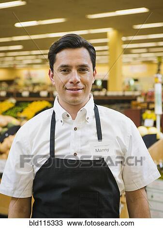Stock Image - Hispanic worker smiling in grocery store. Fotosearch