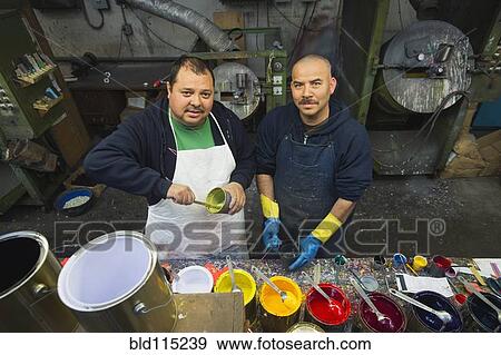 Stock Photo - Hispanic workers mixing paint in workshop. Fotosearch