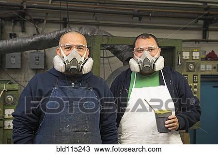 Stock Image - Hispanic workers wearing gas masks in textile factory. Fotosearch