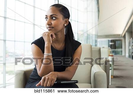 Stock Image - Indian businesswoman sitting in lobby area. Fotosearch