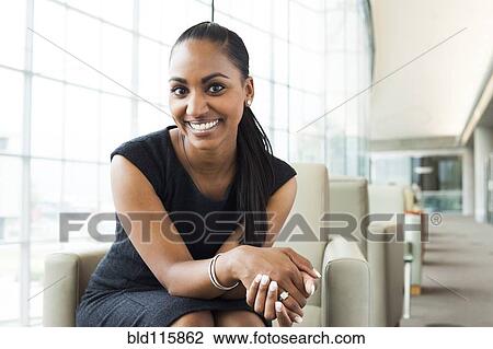 Stock Image - Indian businesswoman sitting in lobby area. Fotosearch