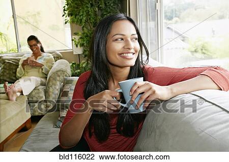 Indian woman having cup of coffee on sofa View Large Photo Image Stock Image - Indian woman having cup of coffee on sofa. Fotosearch