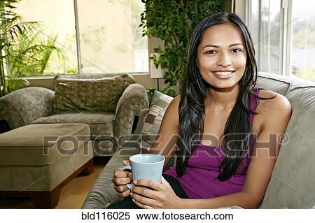 Indian woman having cup of coffee on sofa View Large Photo Image Stock Photography - Indian woman having cup of coffee on sofa. Fotosearch