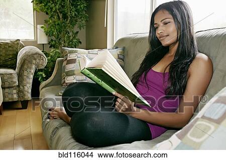 Indian woman reading book on sofa View Large Photo Image Picture - Indian woman reading book on sofa. Fotosearch