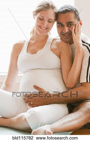 Stock Image - Man hugging pregnant woman's stomach. Fotosearch