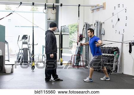 Stock Image - Man working with trainer in gym. Fotosearch