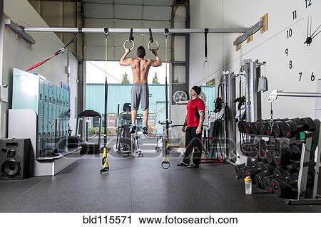 Stock Image - Man working with trainer in gym. Fotosearch