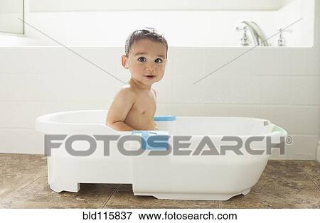 Stock Photo - Mixed race boy having bath in tub. Fotosearch