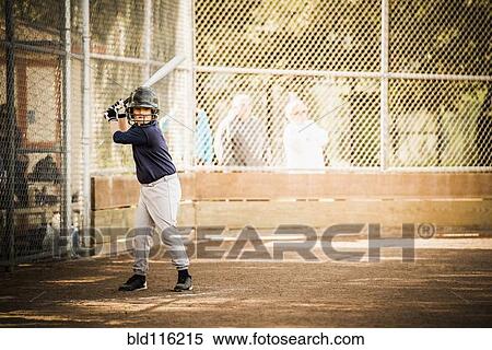 Stock Photography - Mixed race boy playing baseball in field. Fotosearch