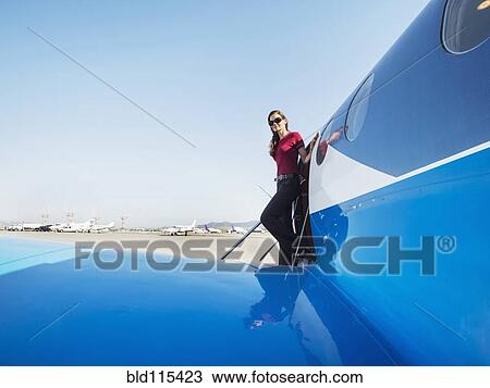 Stock Image - Mixed race businesswoman leaving airplane on runway. Fotosearch