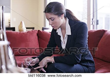 Stock Photo - Mixed race businesswoman painting her nails. Fotosearch